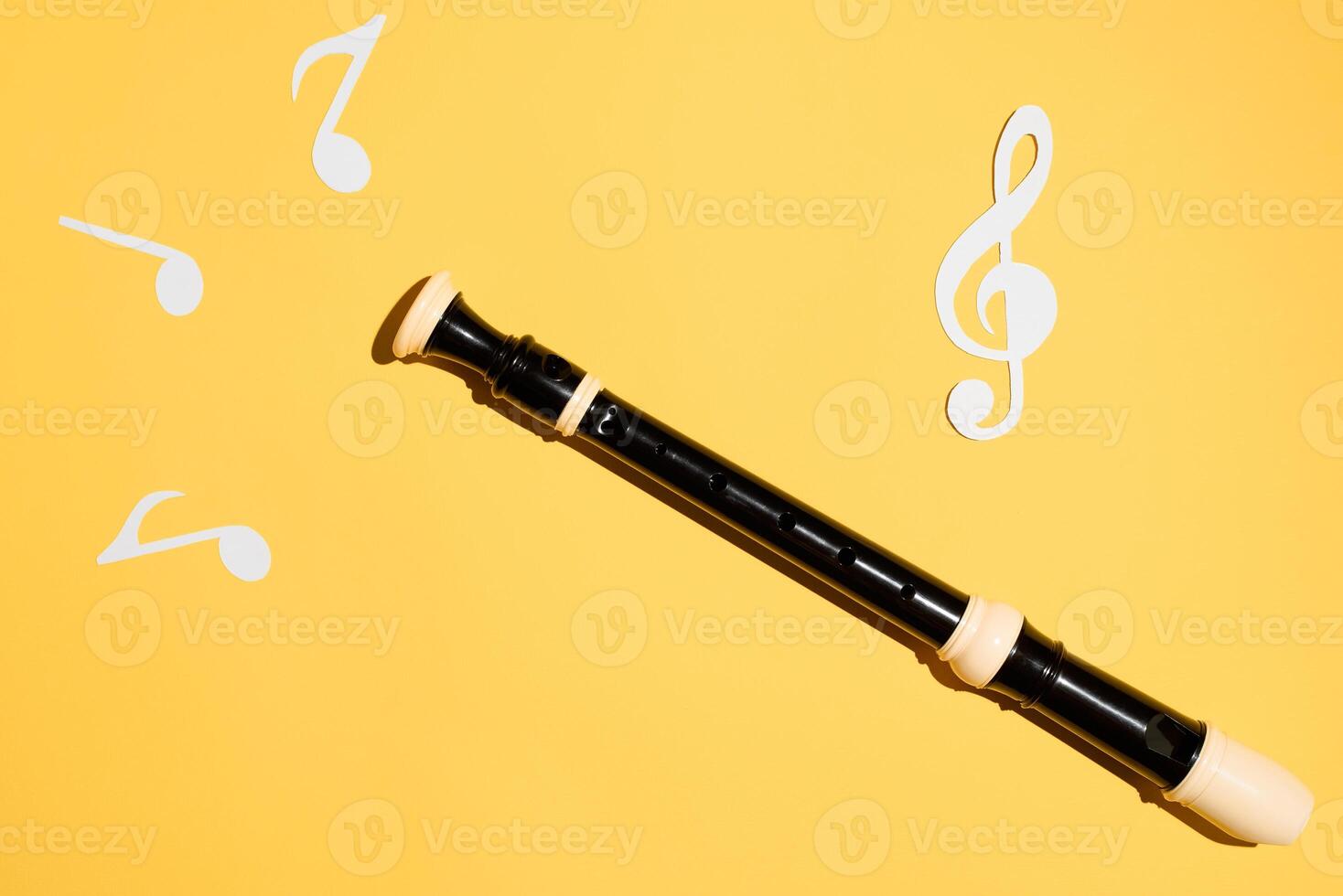 Flute, notes and treble clef, flat lay on a yellow background. Musical classical instrument photo