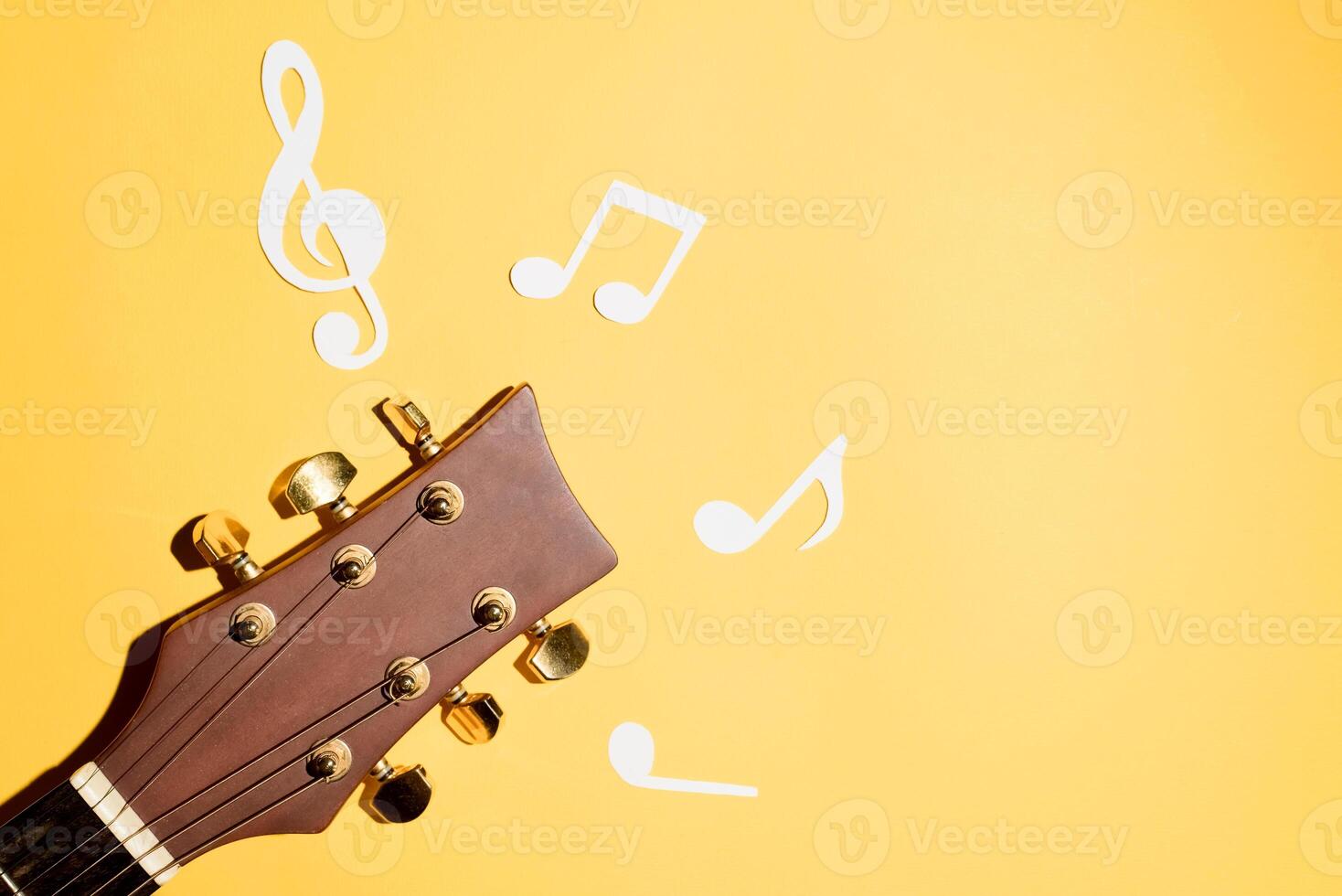 Musical notes and guitar fretboard close up, flat lay on yellow background. Music backdrop photo