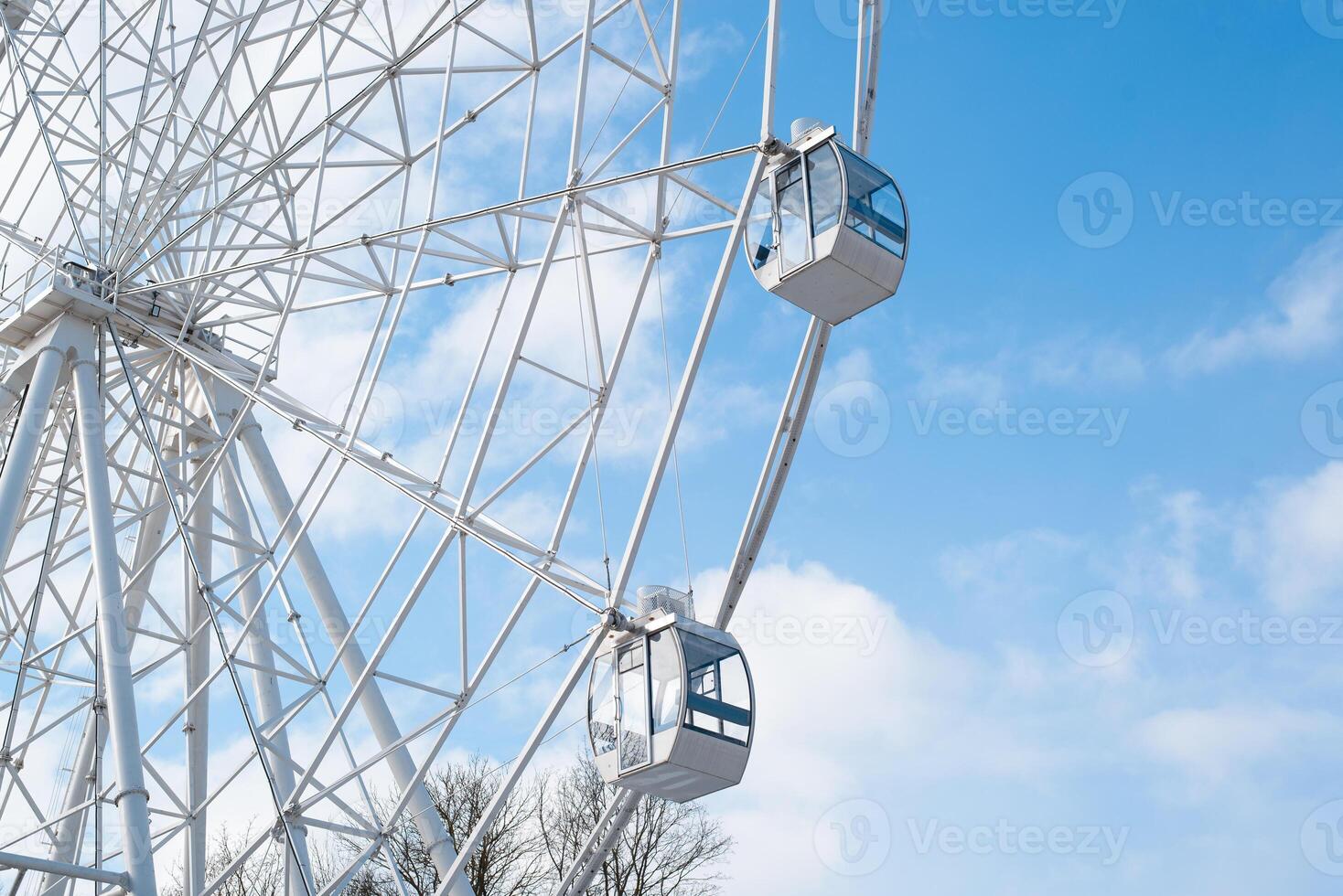 Attraction Ferris wheel in the park against the background of the cloudy sky. Bottom view photo