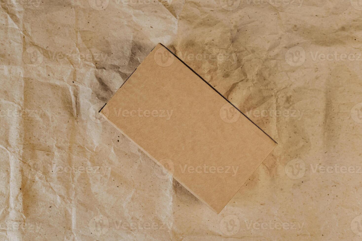 Cardboard box on crumpled craft paper. Flat lay. Delivery concept photo