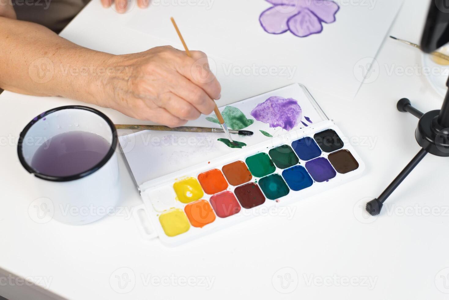 A woman is painting with watercolors on a table photo