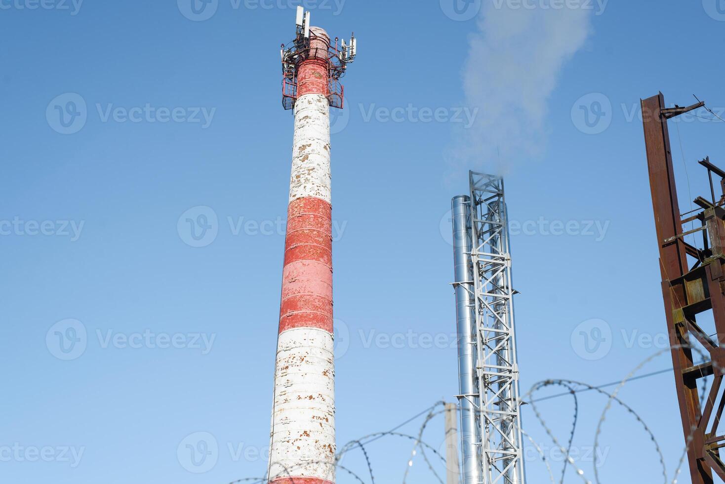 Tower with a pipe. Rising smoke into the clear light blue sky. Environmental pollution concept. photo