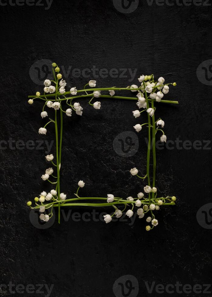 Flower composition. square frame of flowers lilies of the valley on a black background. Flat lay, top view, copy space. Springtime photo