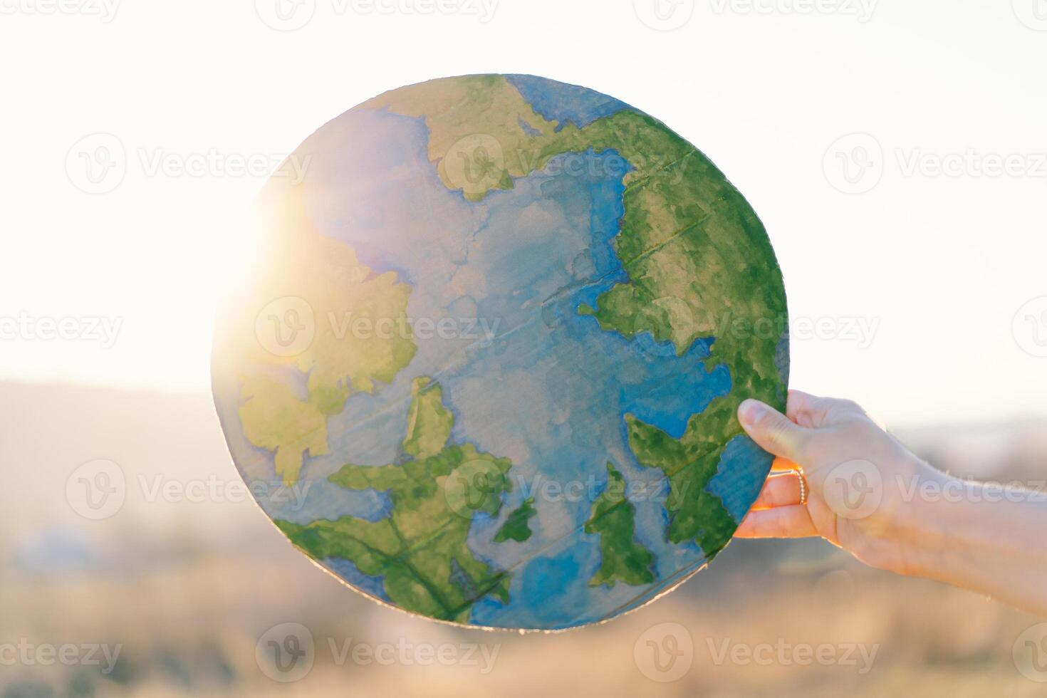 Woman holding planet in hands against green spring background. Earth day photo