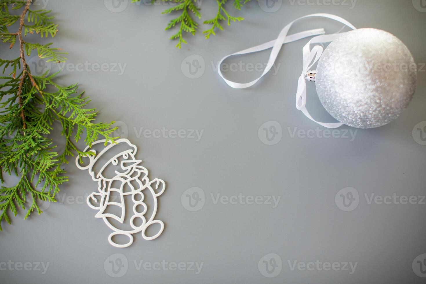 Snowy New Year's ball, thuja and snowman on a gray background photo
