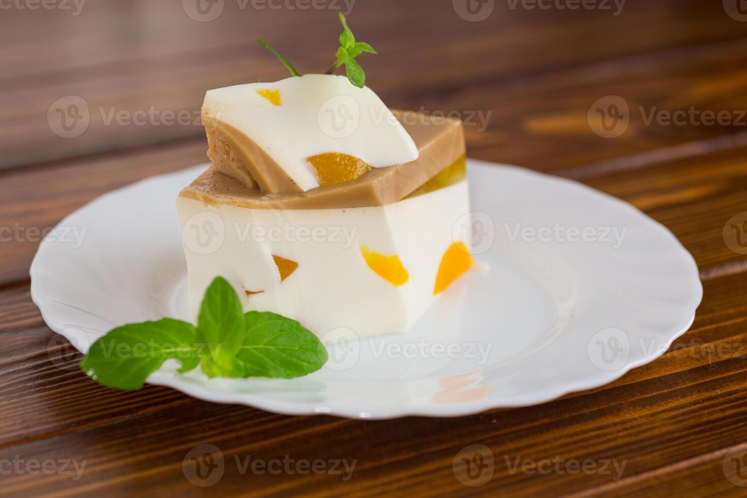 milk fruit jelly dessert with pieces of fruit inside, in a plate.Diet dessert. photo