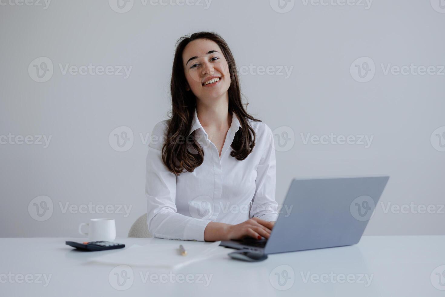 Young woman working at desk with laptop and smiling in a bright office environment photo