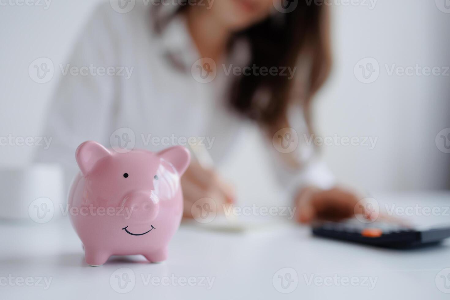 Saving money with a piggy bank while budgeting at a workspace photo
