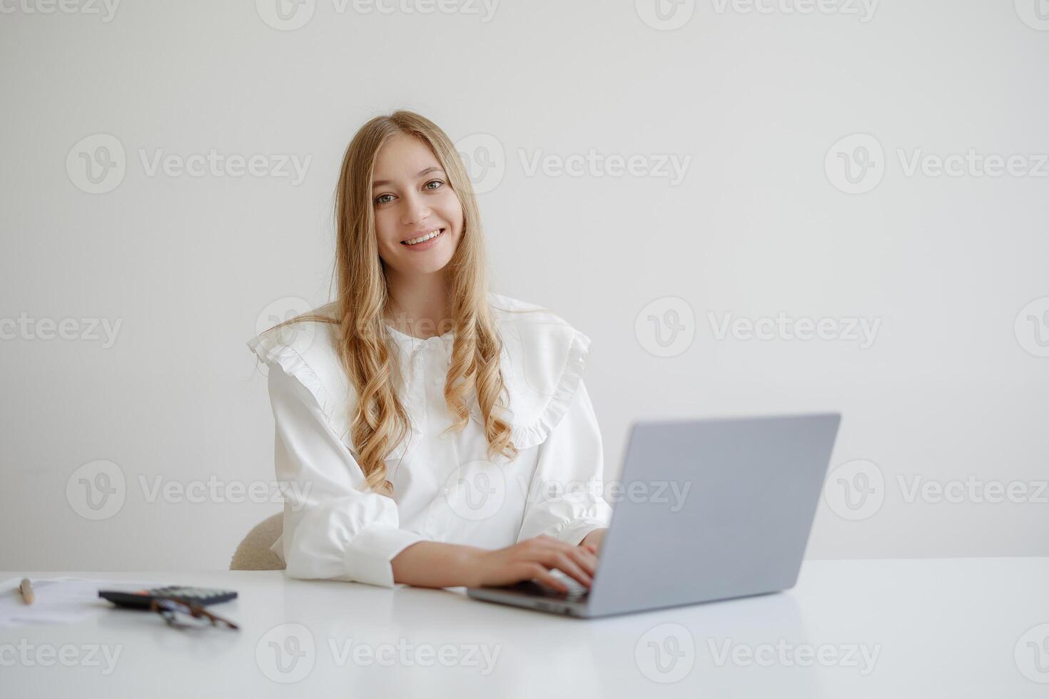Young woman working on a laptop in a bright, minimalistic workspace during daytime photo