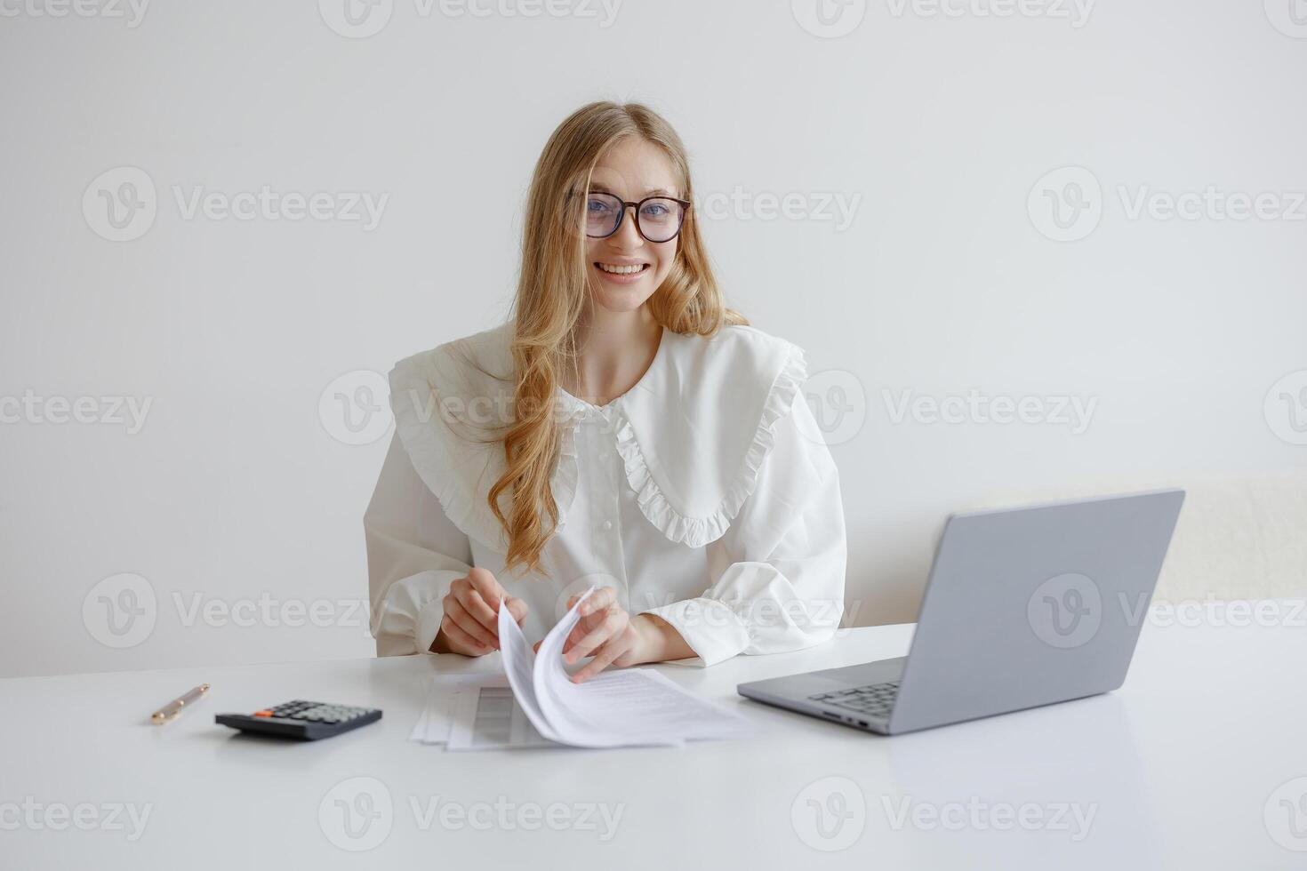 Young woman reviews paperwork while working at a minimalistic desk during daylight hours photo