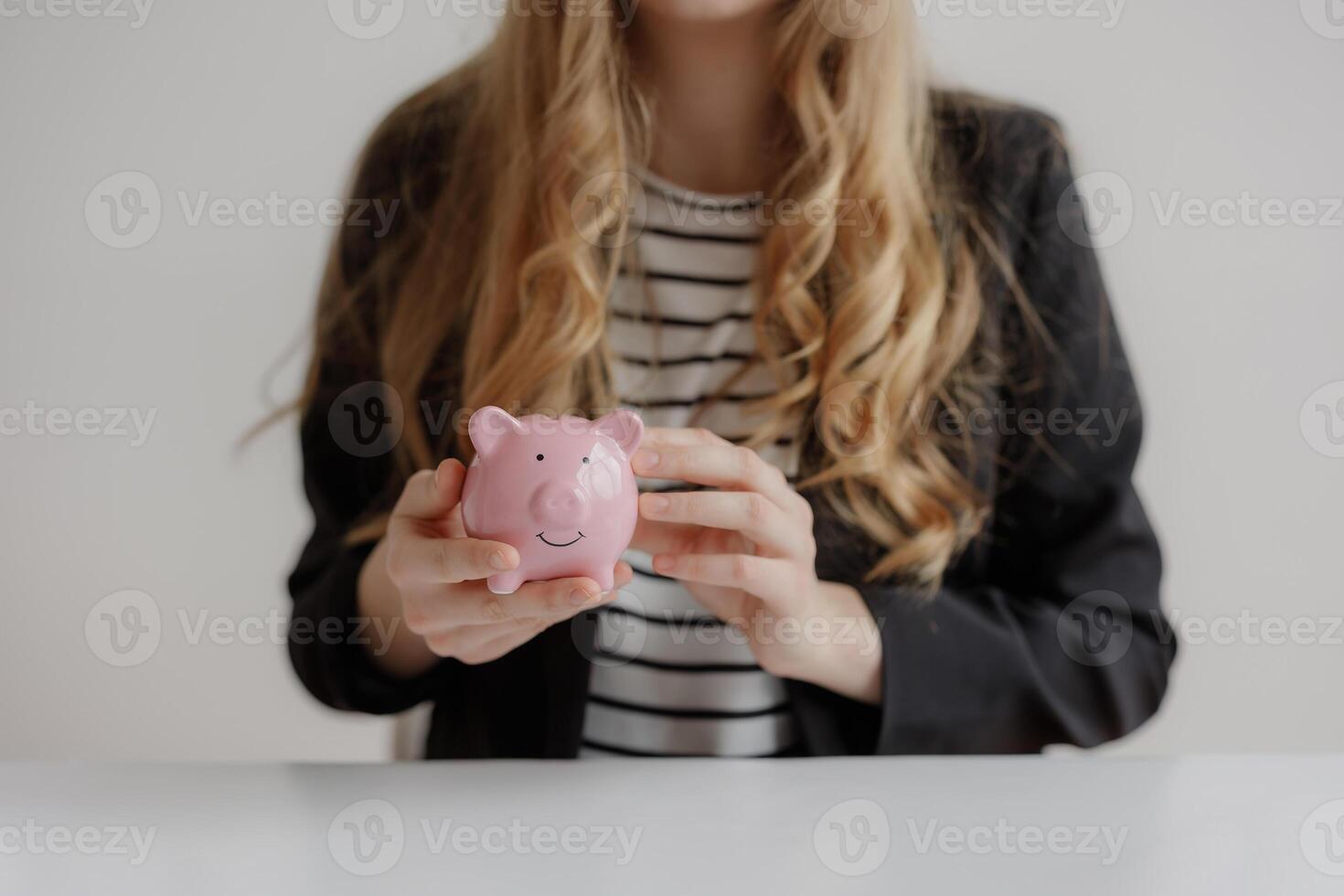 Business professional holding a pink piggy bank while discussing financial plans in a modern office setting photo