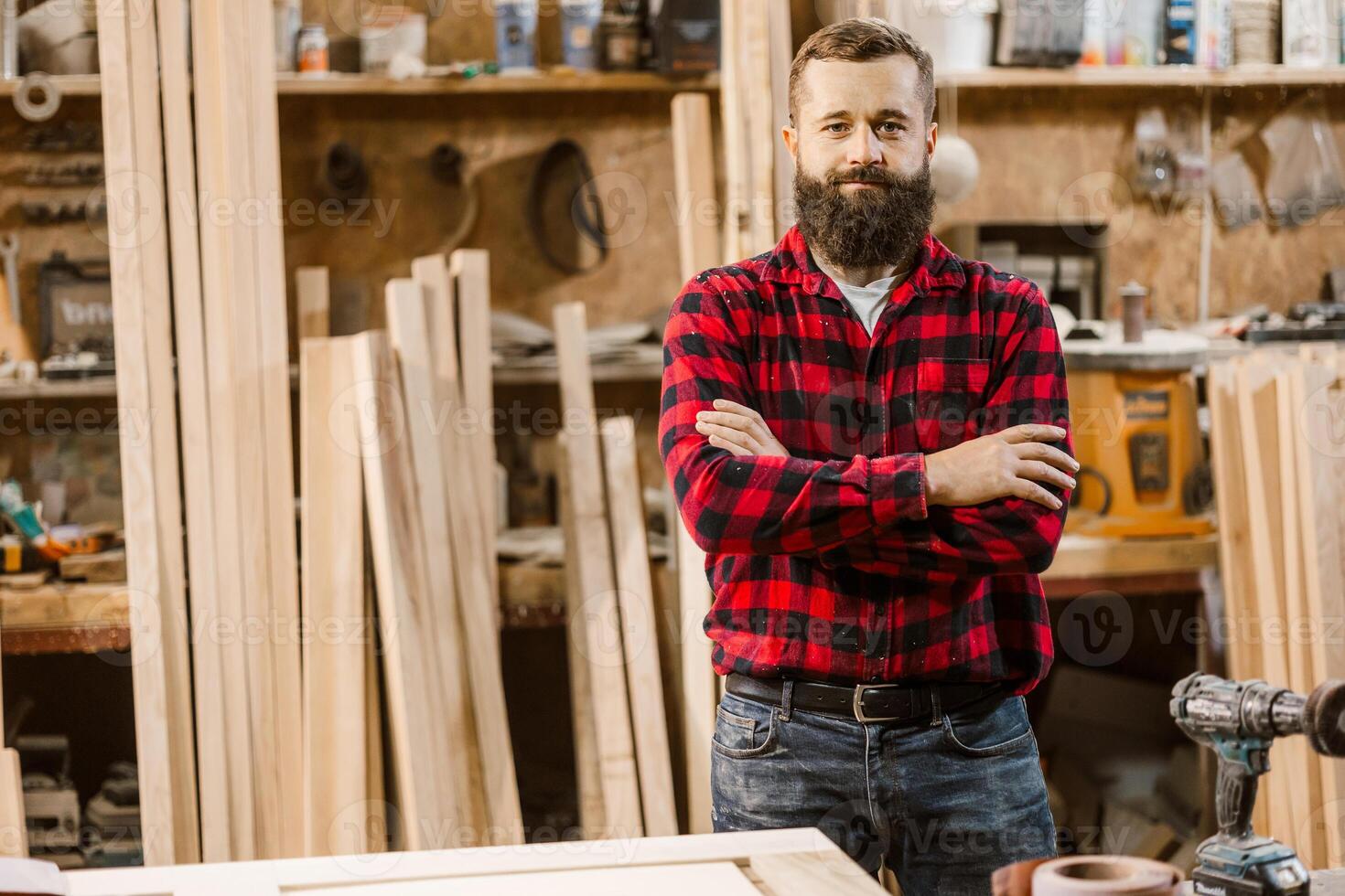 Skilled carpenter poses confidently in a woodworking workshop surrounded by tools and wooden materials photo
