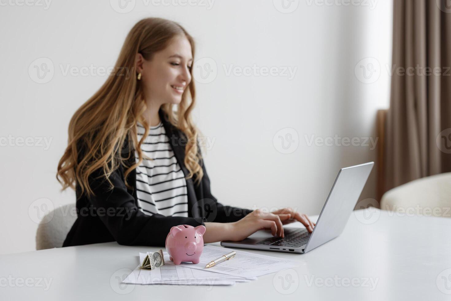 Young woman managing finances using a laptop in a minimalist workspace during the daytime photo