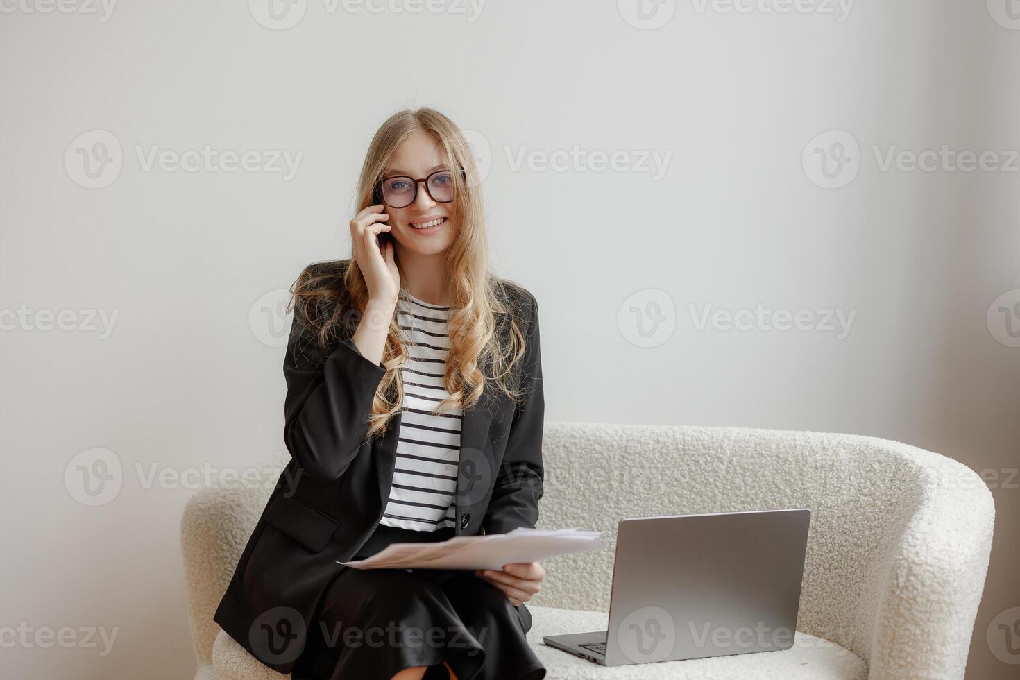 Businesswoman engages in a phone conversation while sitting on a couch in a modern office setting photo