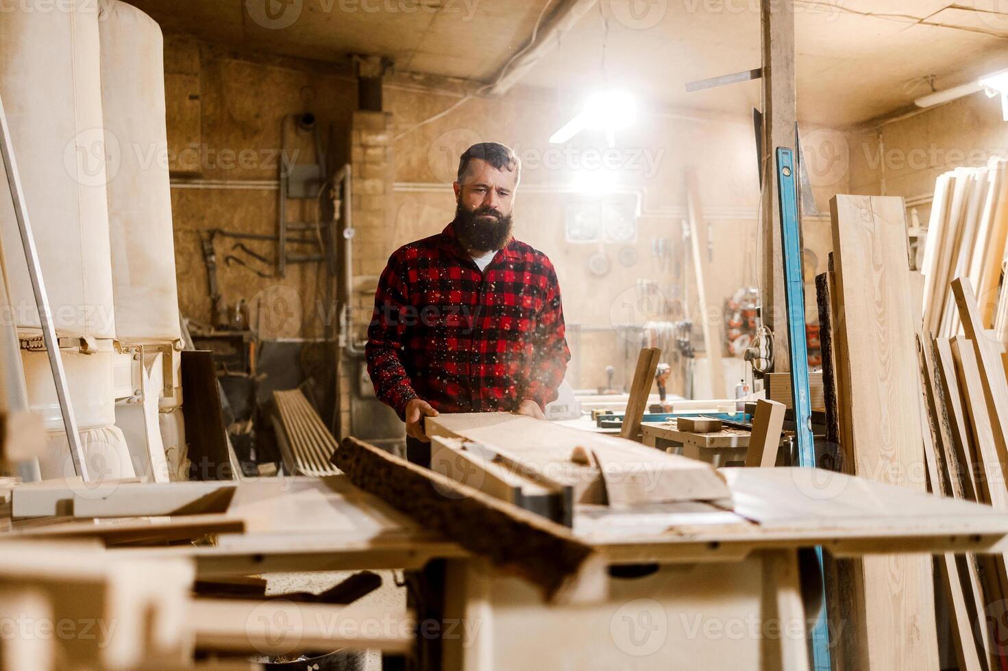 Craftsman working in a woodworking shop surrounded by tools and wood materials during the day photo