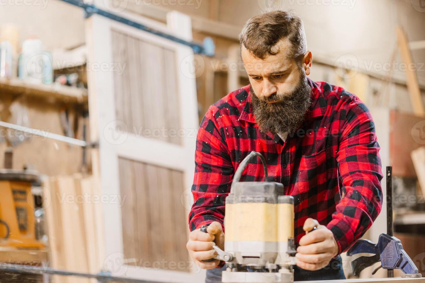 Carpenter uses router to craft wooden furniture in workshop during day photo
