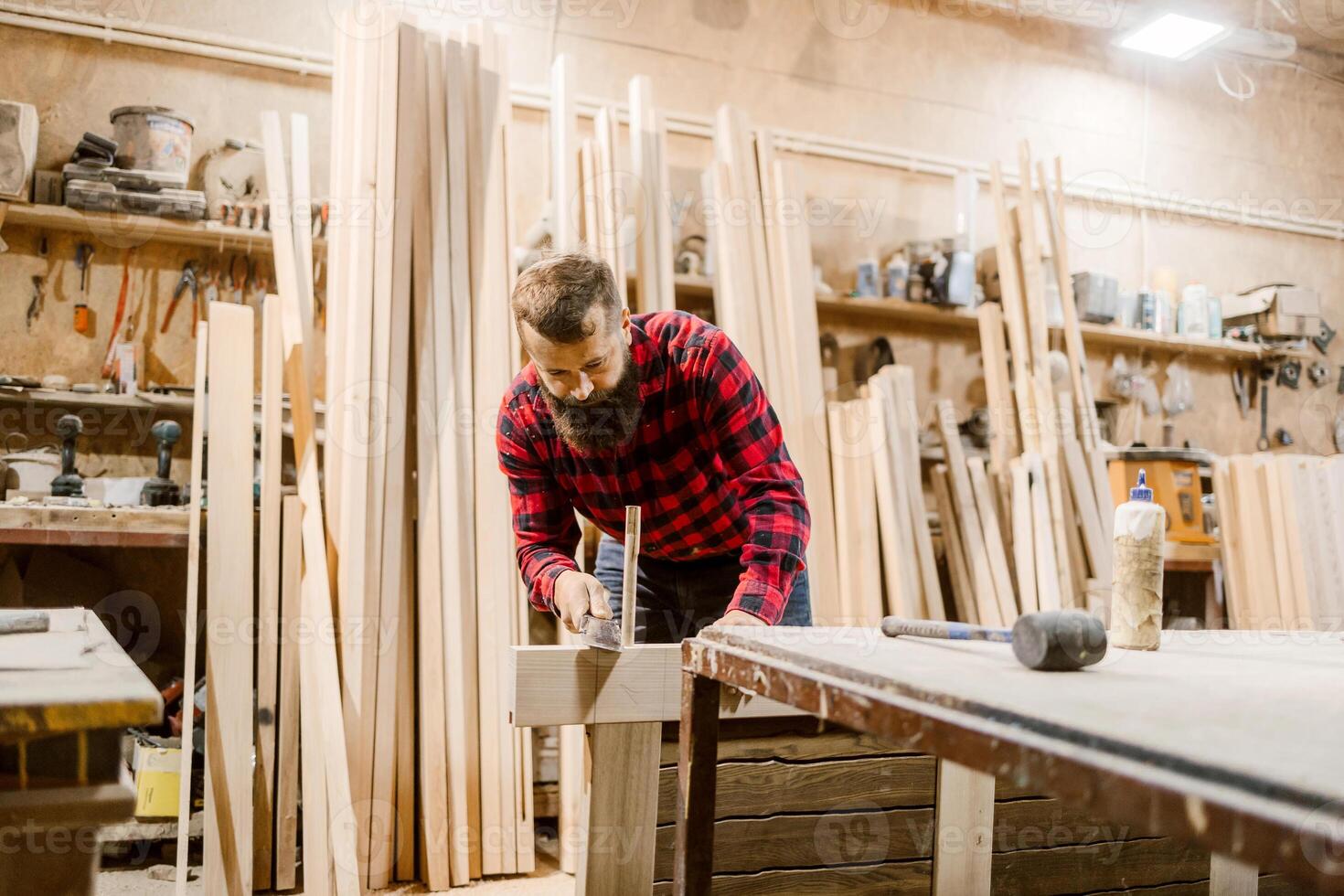 Carpenter working diligently in a woodworking shop on a rustic project surrounded by timber photo