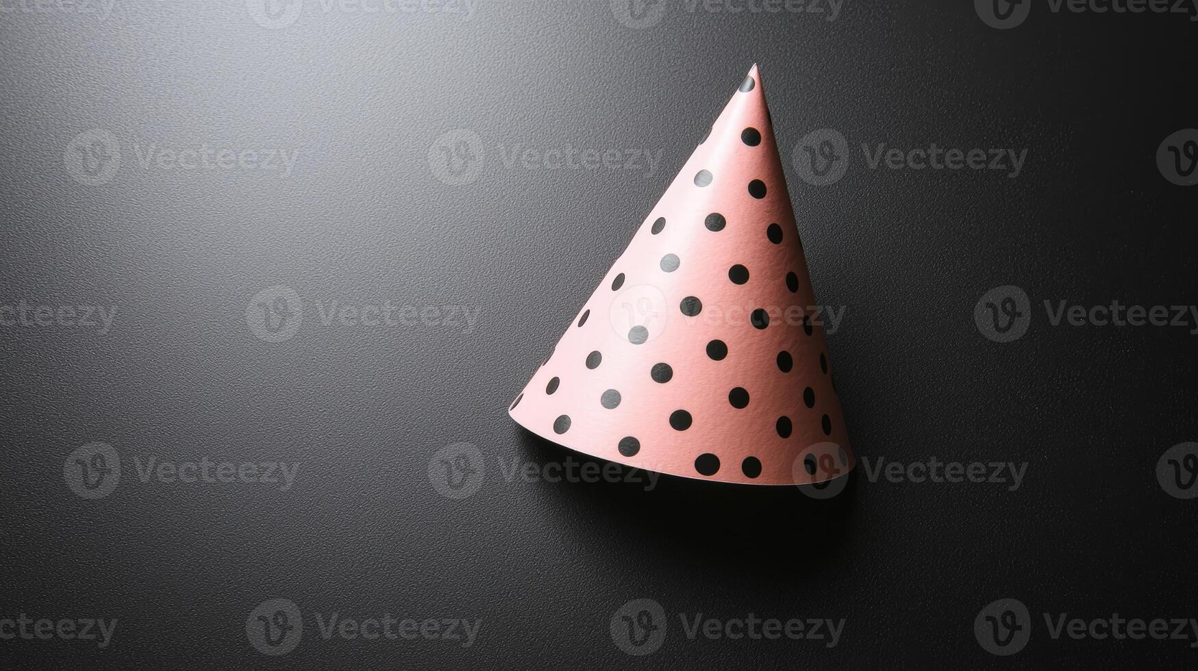 A pink party hat with black polka dots on a dark background photo