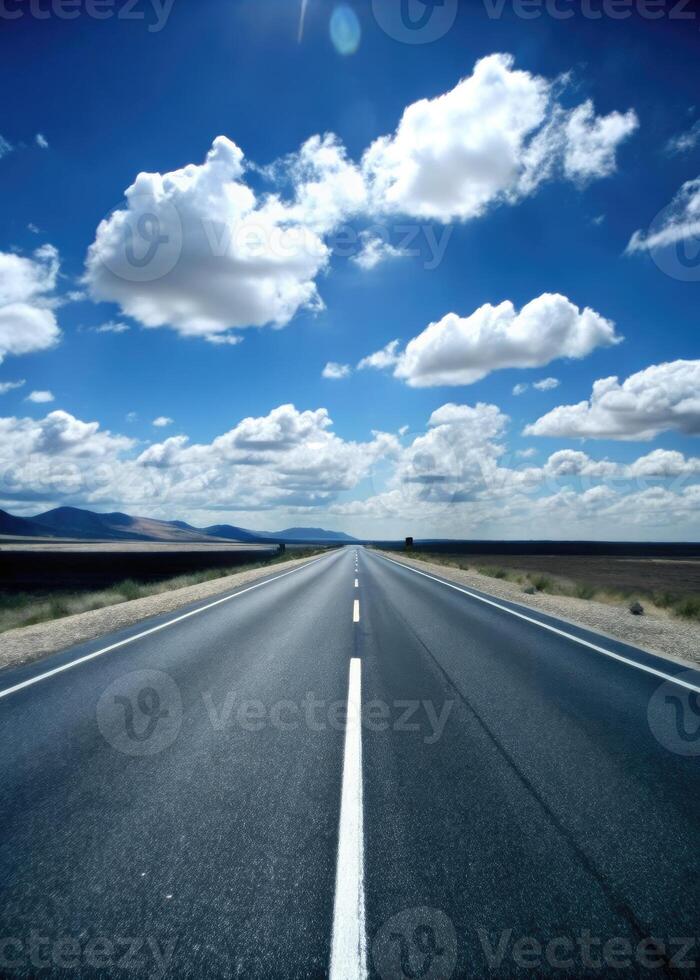 Long open road leading towards a horizon filled with fluffy clouds. photo