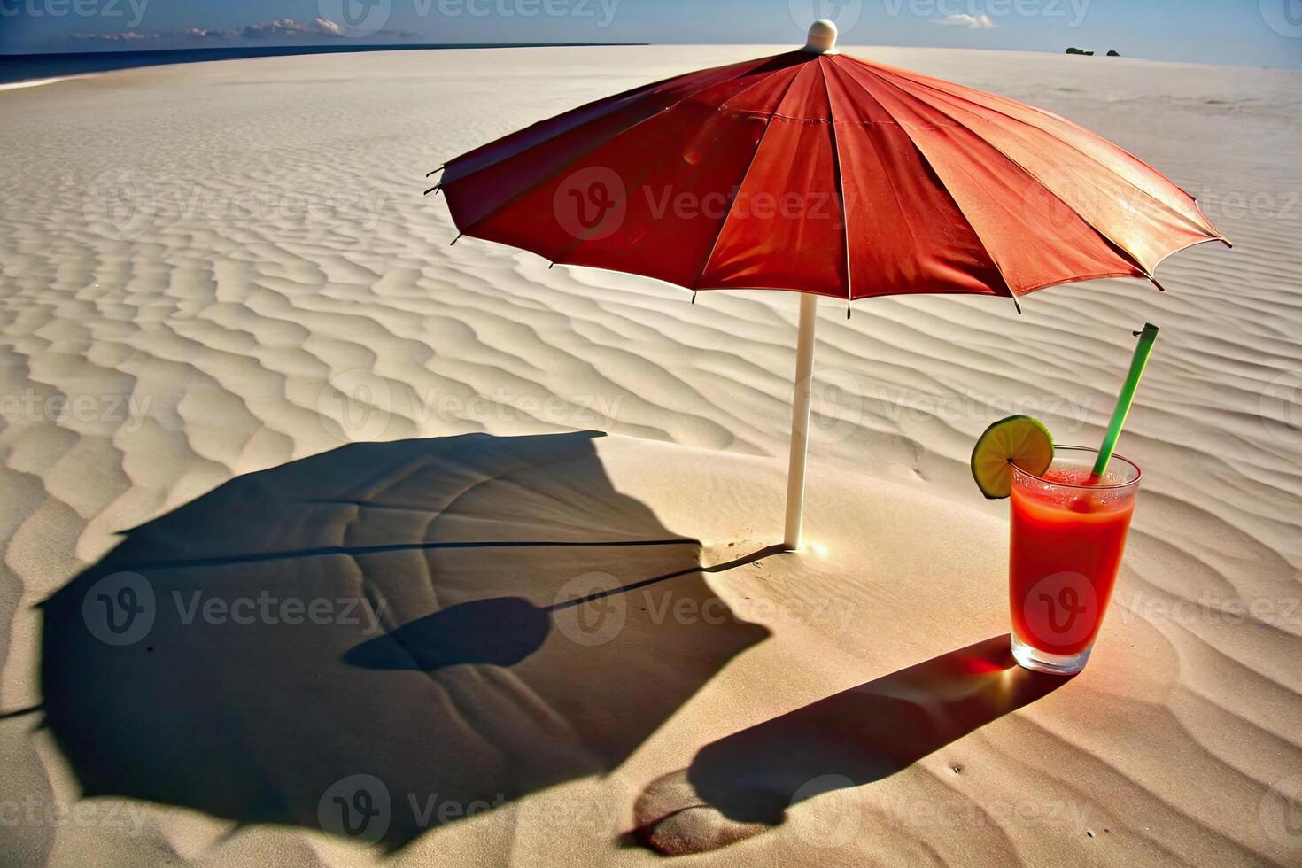 Sun umbrella casting shade on a sandy beach with a cool drink placed nearby. photo