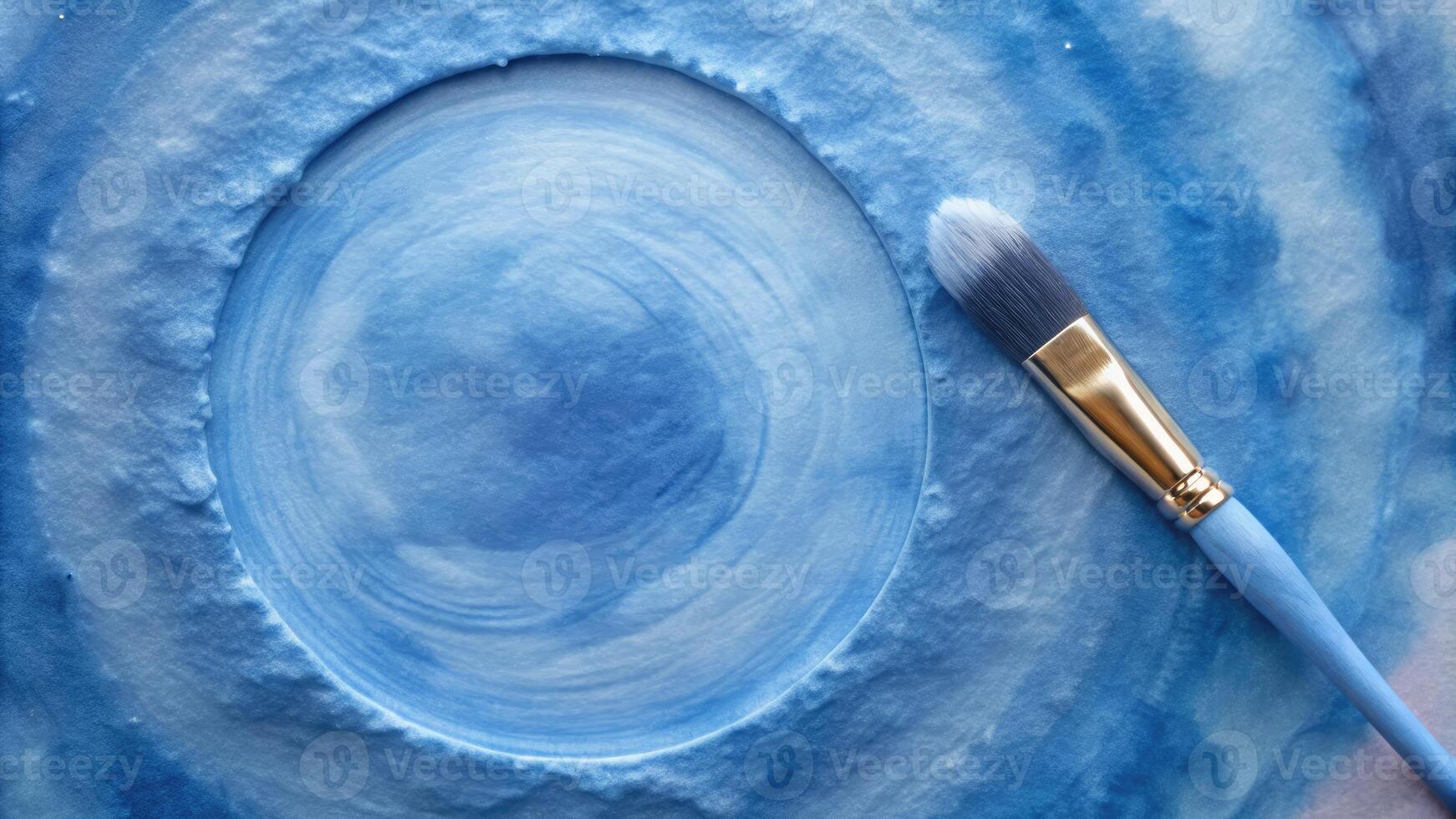 Circular canvas with shades of blue and a paintbrush. photo
