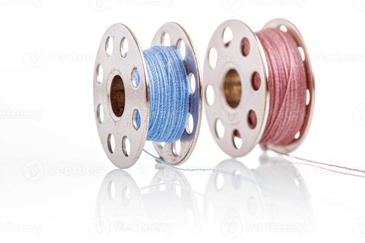 macro spools of blue and pink thread on a white background photo