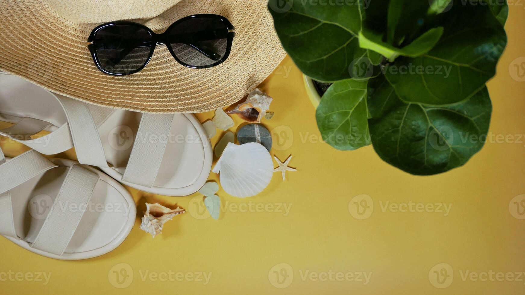 Travel vacation mood layout lifestyle spa wellness concept with beach accessories and copy space. Top view flat lay background, including straw hat, sunglasses, sandals, seashells and pebbles photo