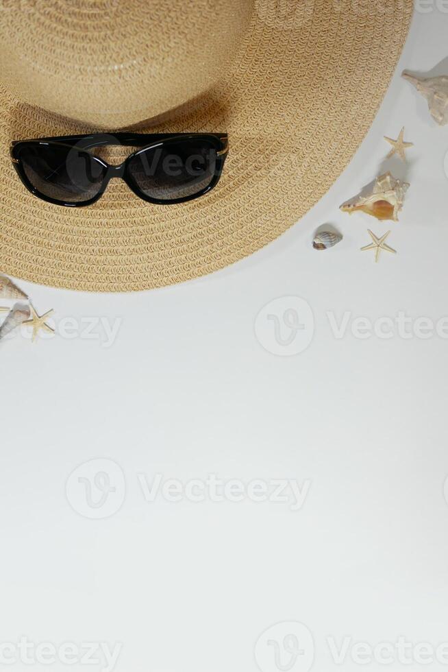 Summer travel mood layout lifestyle spa or wellness concept with beach accessories and copy space. Top view flat lay background, including straw hat, sunglasses, seashells and pebbles photo