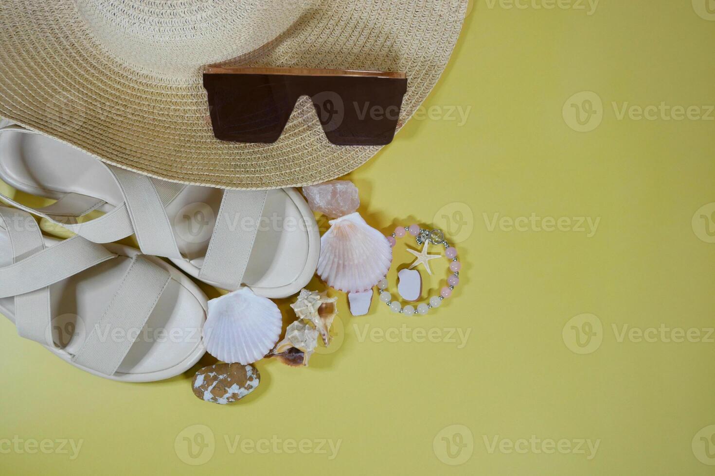 Summer travel vacation mood layout lifestyle wellness concept with beach accessories and copy space. Top view flat lay background, including straw hat, sunglasses, sandals, seashells and pebbles photo