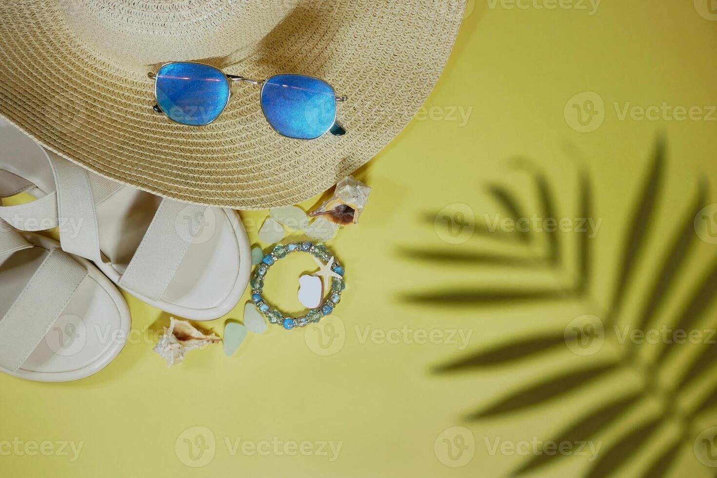 Summer vacation mood layout lifestyle spa wellness concept with beach accessories and copy space. Top view flat lay background, including straw hat, sunglasses, sandals, seashells and pebbles photo
