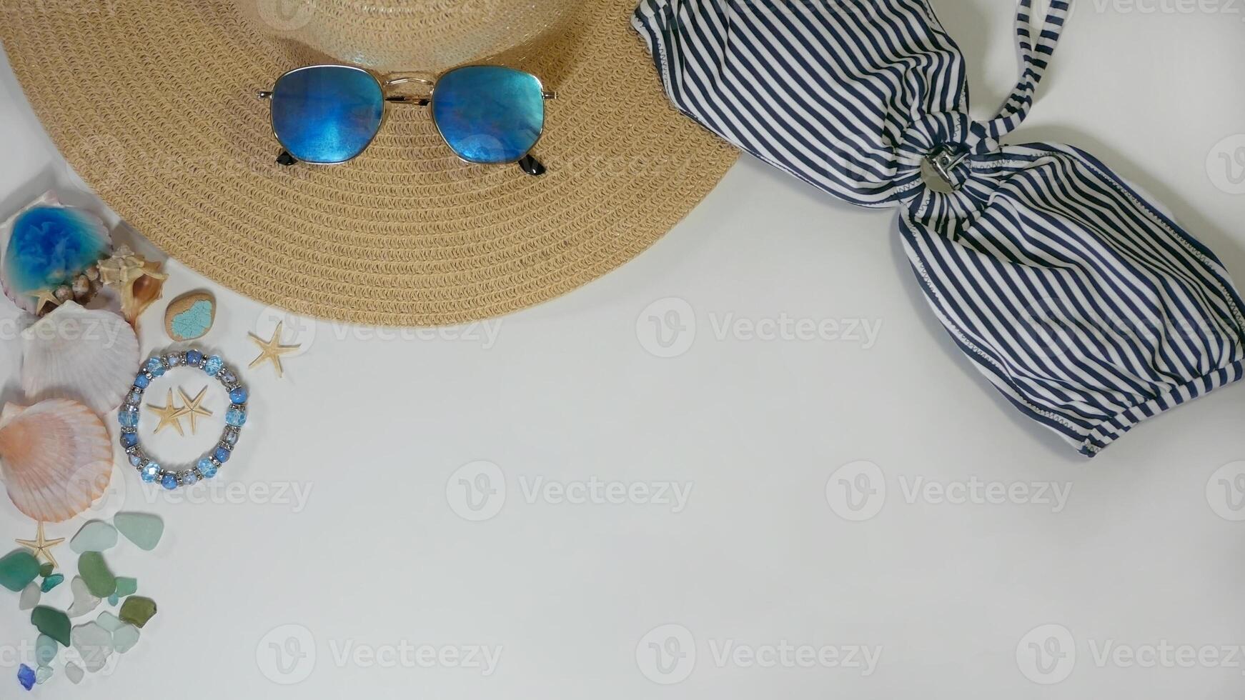 Summer travel layout lifestyle spa wellness concept with beach accessories and copy space. Top view flat lay background, including straw hat, sunglasses, swimsuit, seashells and pebbles photo