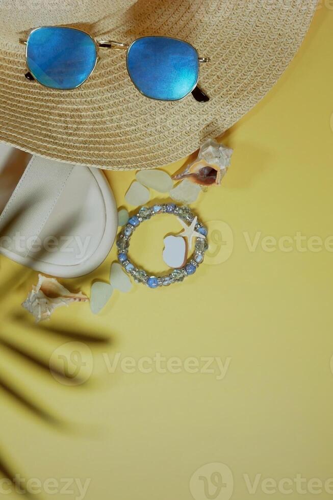 Summer travel vacation mood layout lifestyle spa wellness concept with accessories and copy space. Top view flat lay background, including straw hat, sunglasses, sandals, seashells and pebbles photo