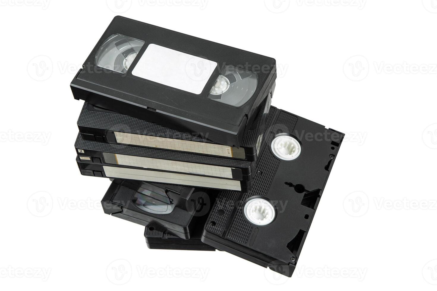 Vintage stack of black VHS cassettes with handwritten labels and visible reels photo