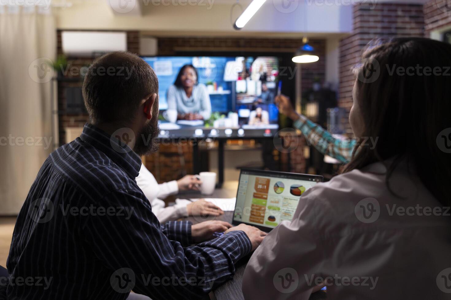 Diverse professionals engaged in a conference, sharing marketing strategies and financial planning. Late night teamwork and group discussions during virtual meeting in modern workspace. photo