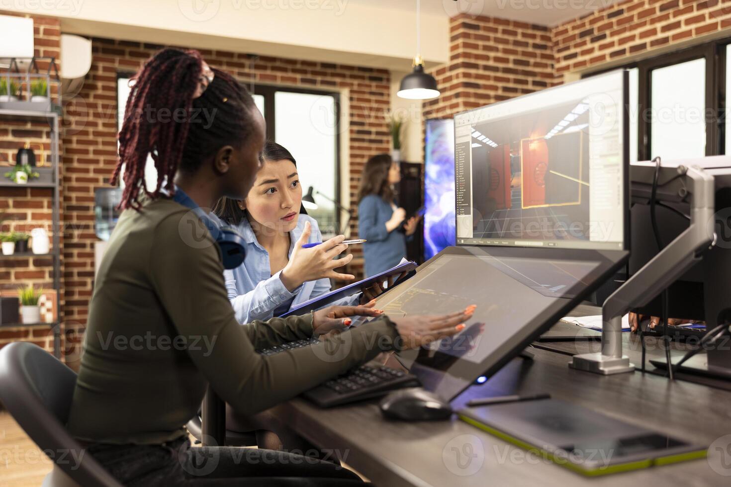 Diverse digital artists working on graphic design and multimedia projects, using a computer and touchscreen monitor. Black and asian women developing creative applications in collaborative workspace. photo