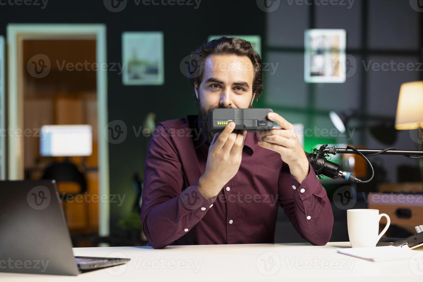Tech specialist filming review of newly released portable V mount battery in home studio. Online star recording unboxing of lithium li-ion charging gadget for subscribers photo