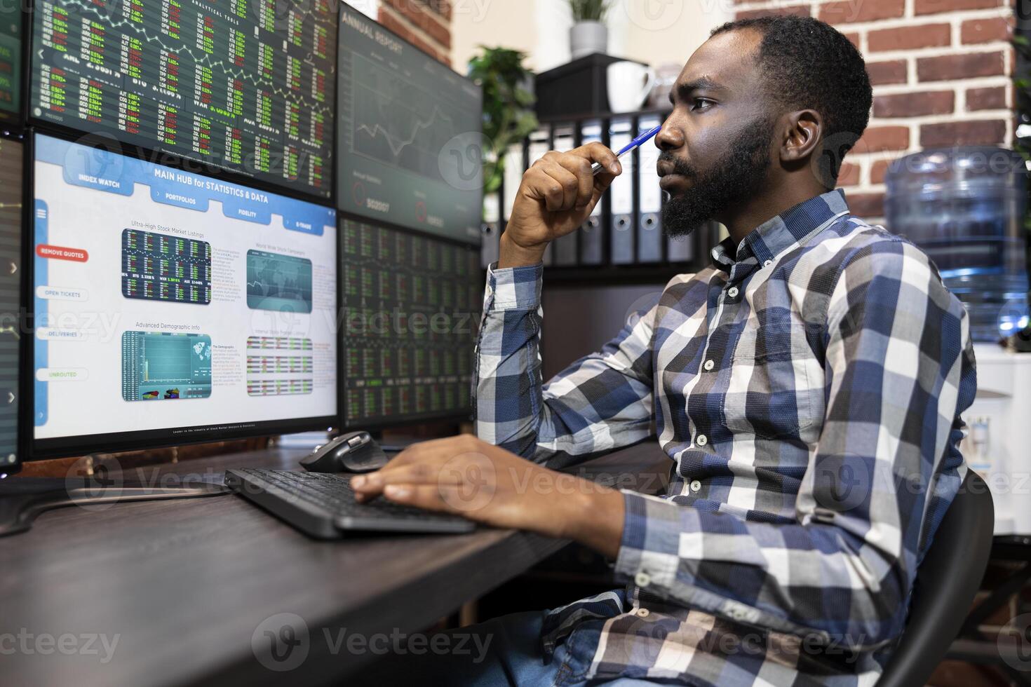 Young forex trader analyzing real time financial data on different computer screens at night in office. Male entrepreneur in deep thoughts, focused on the trading software and stock market charts. photo