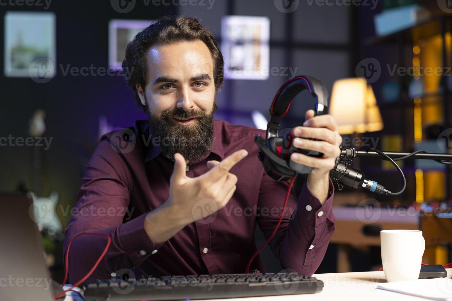 Cheerful content creator endorsing wired gaming headphones for online streaming platforms viewers. Man excited to promote newly launched music listening device, doing influencer marketing photo