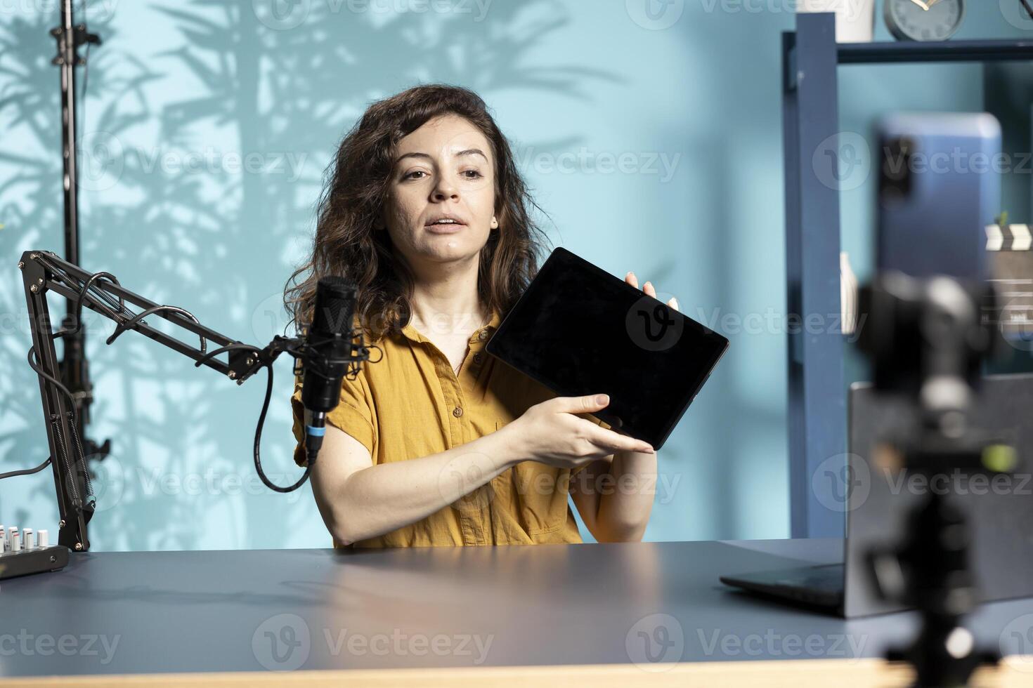 Tech guru presenting tablet from brand sponsoring , urging viewers to purchase it. Technology expert does influencer marketing by advertising digital device to audience photo