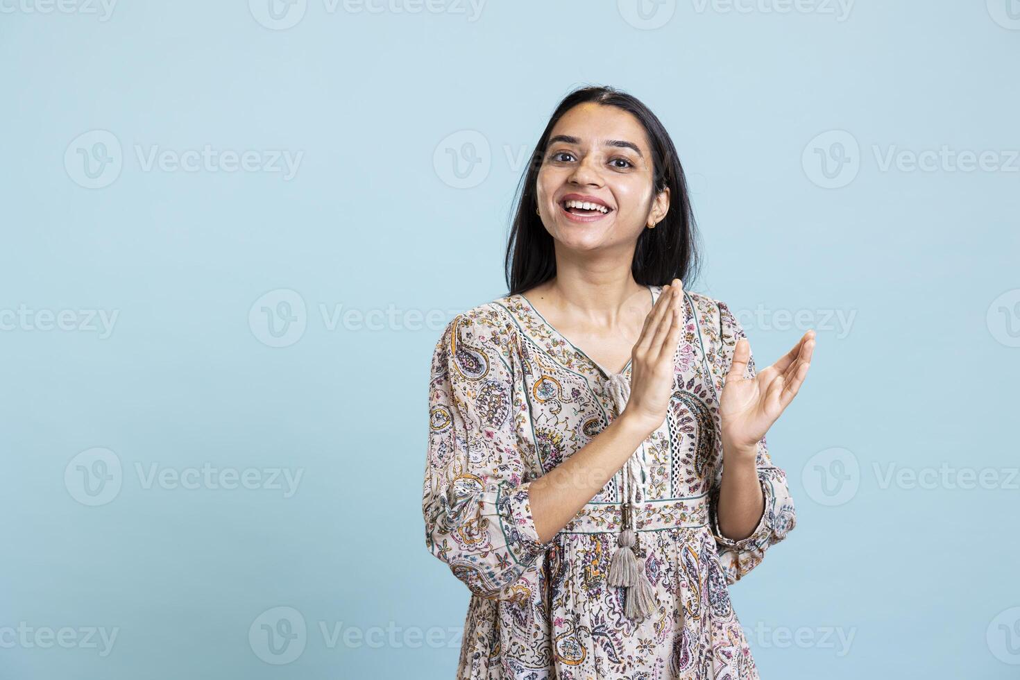 Confident pleased woman applauding in front of the camera and cheering for success, standing ovation for personal achievement. Indian girl ecstatic in admiration clapping hands in studio. photo