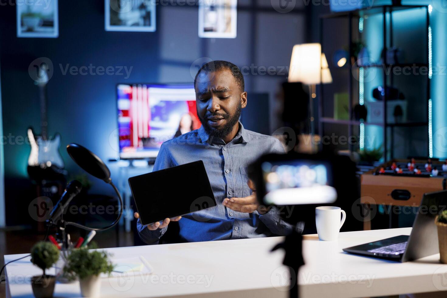 BIPOC content creator analyzing newly released gaming tablet received from sponsor, doing honest review for online streaming channel. Media star reviewing digital device brand photo