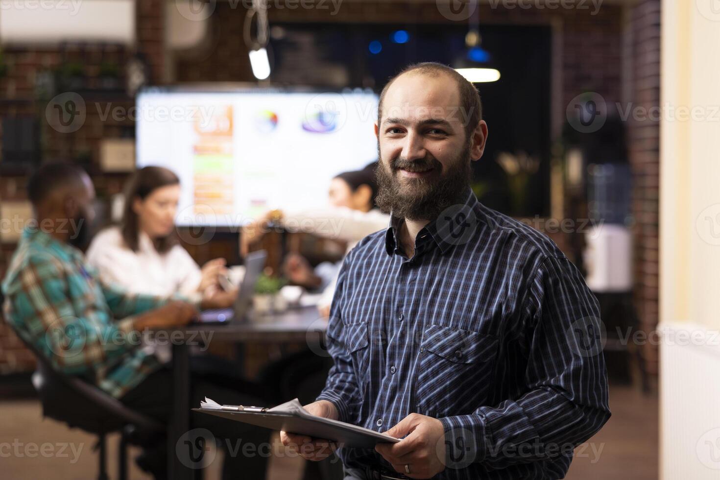Determined businessman in checkered shirt ready to review project planning details in office. The modern workspace, late night teamwork and digital analytics highlight productivity. photo