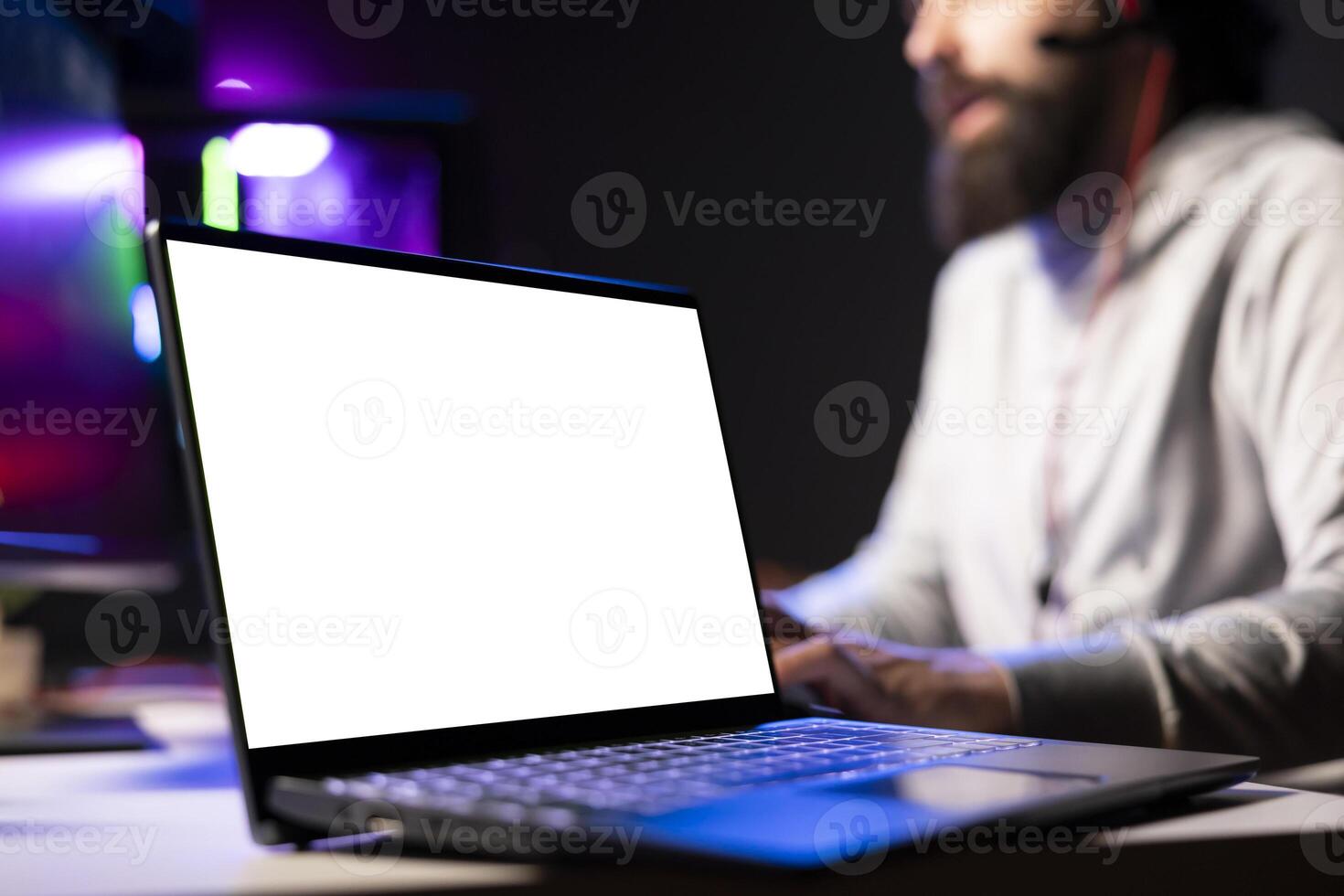 Person in dimly lit apartment playing games on isolated screen laptop at computer desk, enjoying day off from work. Gamer battling enemies in online multiplayer shooter on mockup notebook device photo