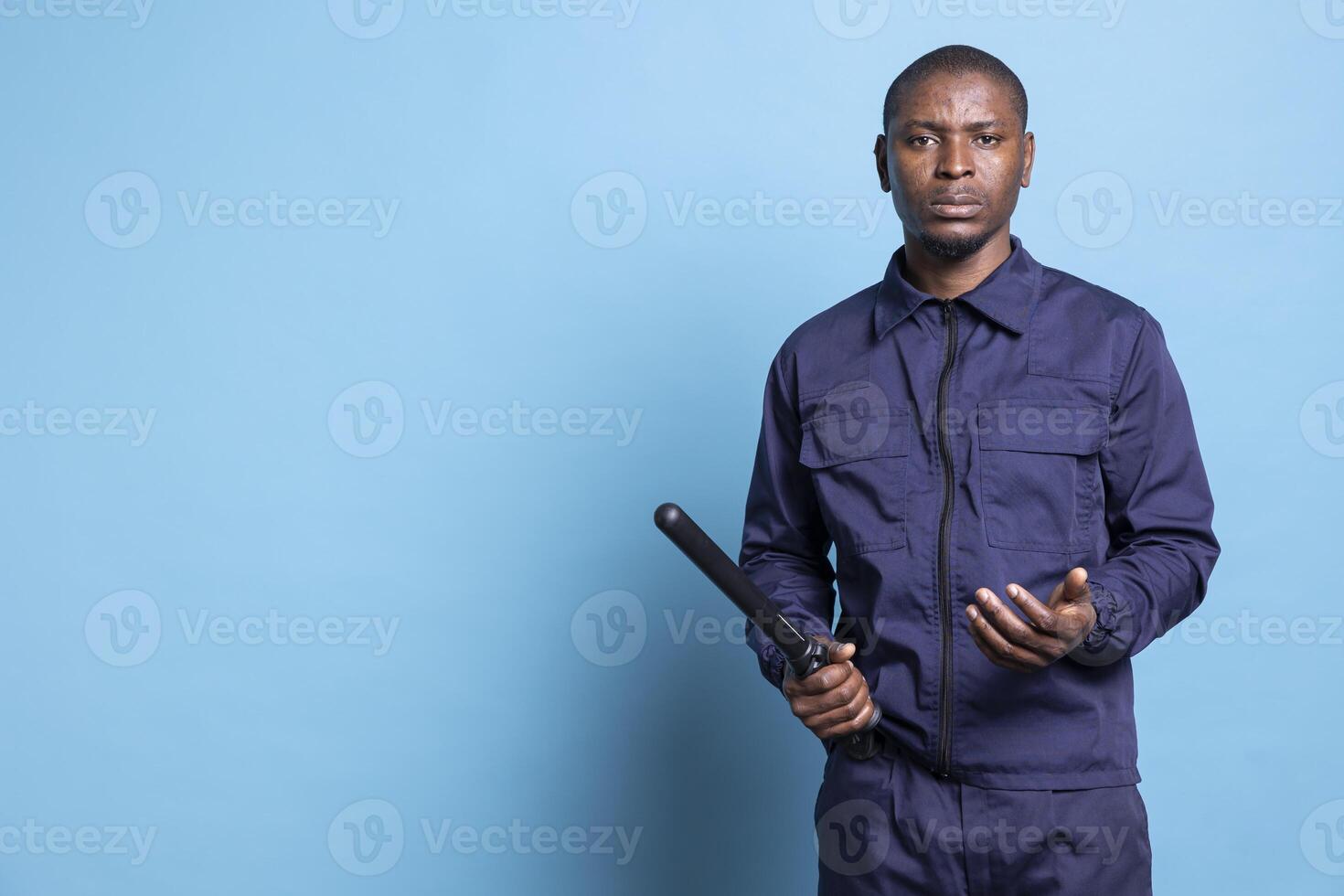 Skilled serious security guard prepares a protection baton in his hands, getting ready for any emergency defense or combat to safeguard the perimeter. African american agent on protecting duty. photo