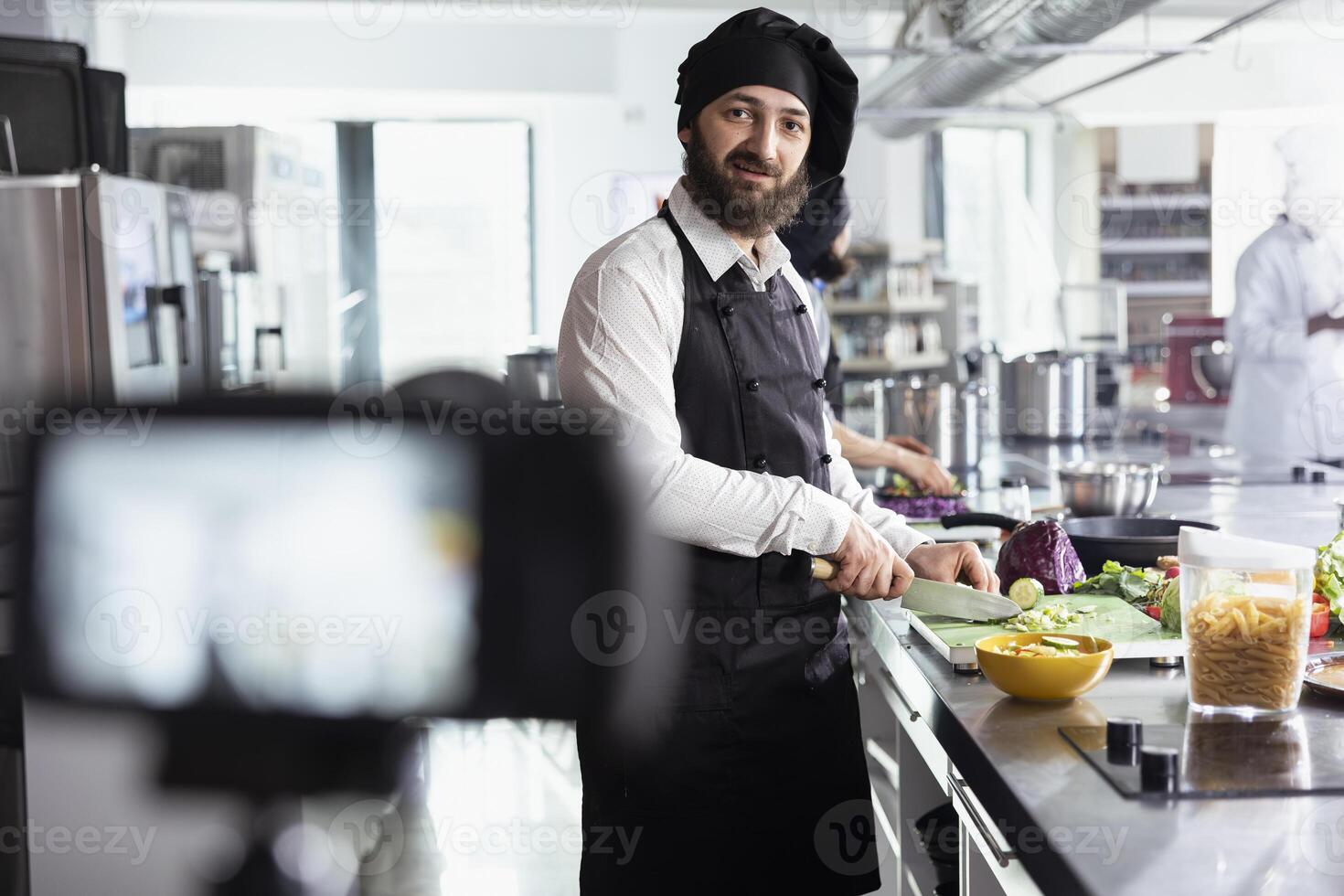 Chef recording cooking class for online culinary school platform, guiding beginners through essential kitchen techniques on tutorial. Male cook teaching culinary arts skills. photo