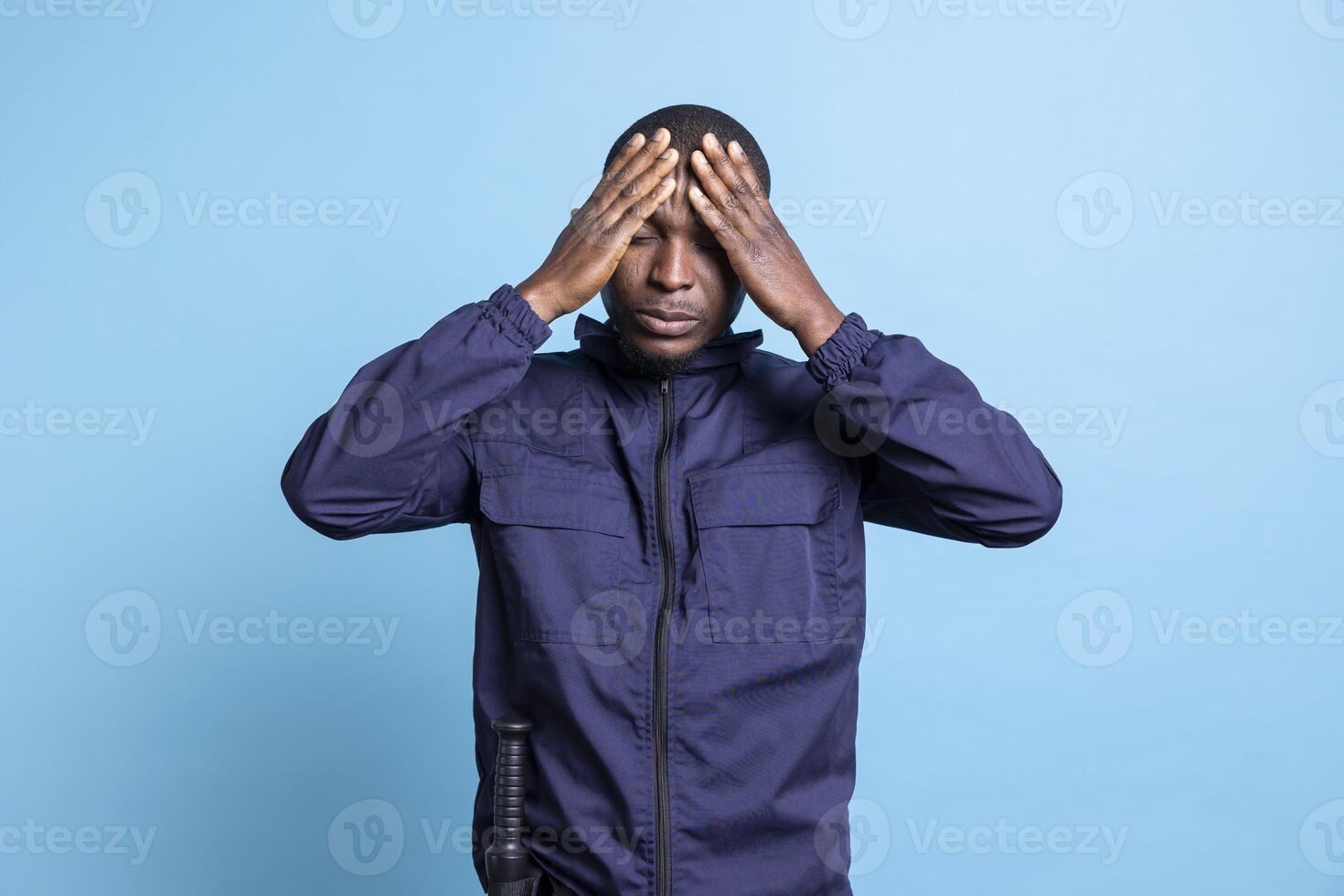 Security guard has a painful headache in front of camera, dealing with a lot of stress and fatigue while on duty. Bodyguard feeling distraught and in despair, suffering from sickness and flu. photo