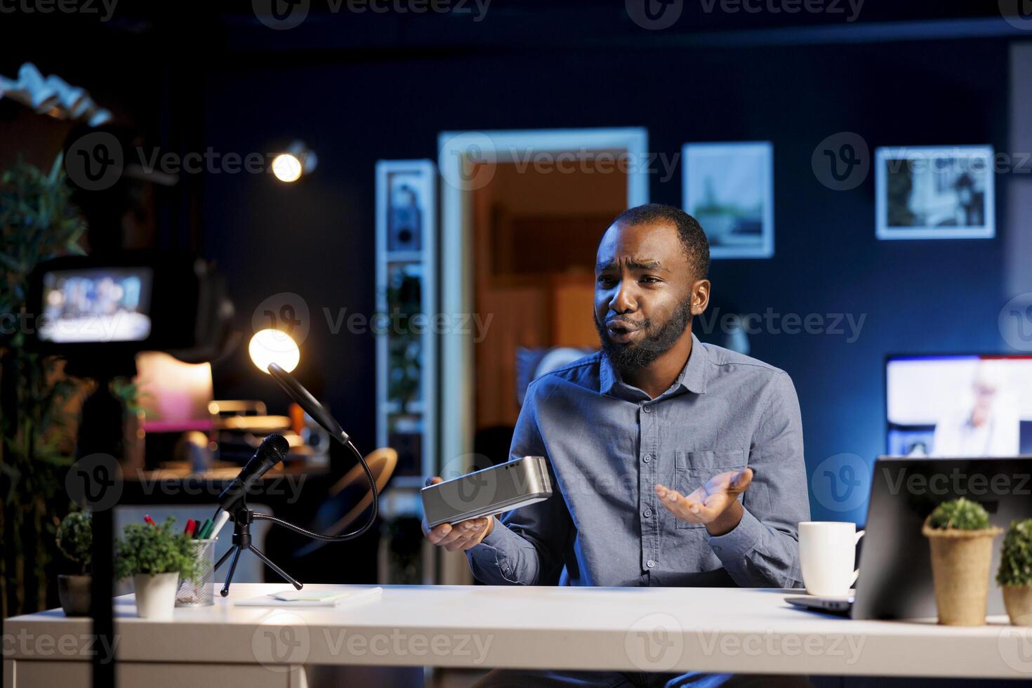 African american man reviewing portable speaker, disappointed about low quality sound coming from it. Content creator filming for online channel, unhappy with audio device product photo