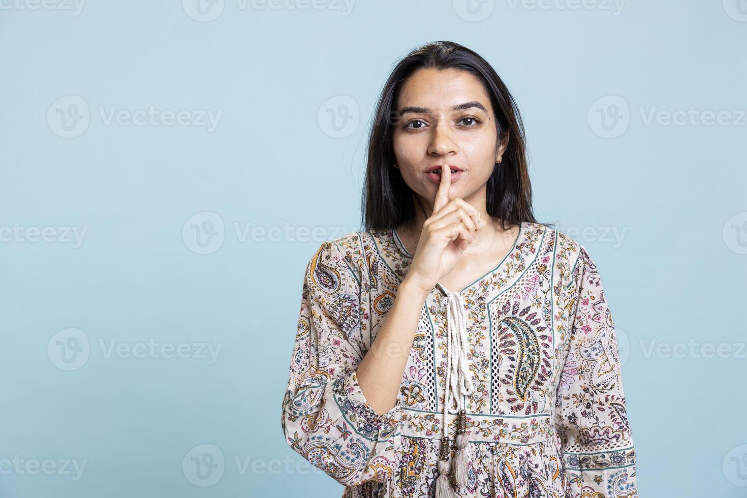 Authoritative woman doing shushing hand gesture in front of camera, demanding secrecy and being irritated by noise. Indian person complaining, placing finger on lips and doing quiet warning sign. photo