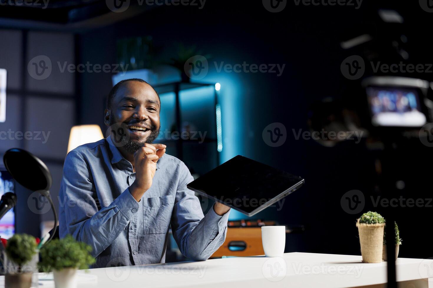 Cheerful content creator filming tech tutorial on how to do maintenance on laptop, presenting internal parts. Technology media star in living room teaching subscribers to fix notebook device photo
