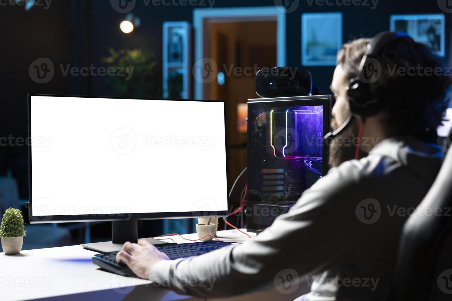 Man using gaming station mockup monitor, excited to finally relax by playing videogame on PC at computer desk late at night. Gamer starting game on isolated screen computer, battling foes photo
